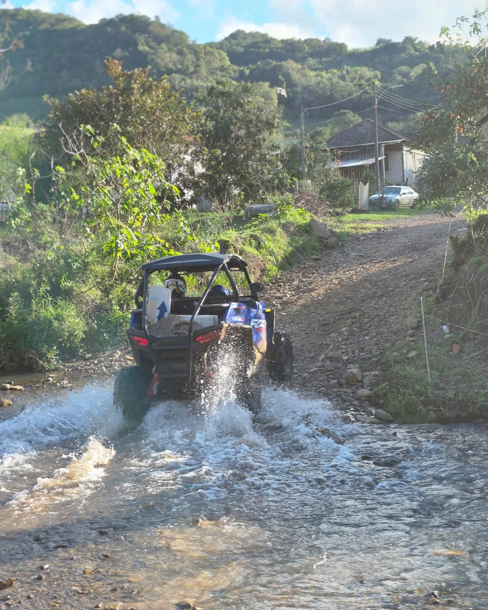 Polaris RZR atravessando o leito de um arroio e levantando água